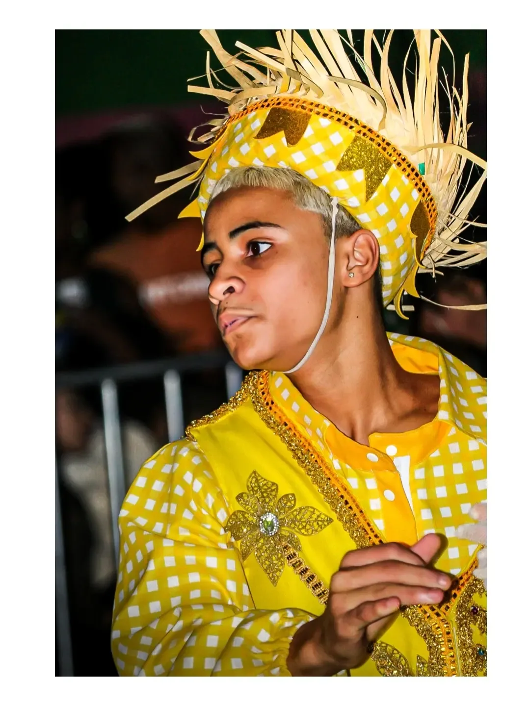 Jovem com camisa amarela e chapéu de palha decorado durante uma festa junina.