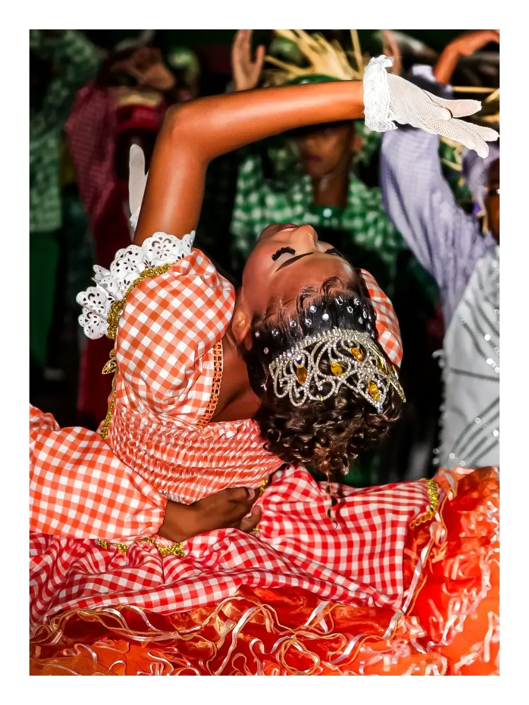 Dançarinos com roupas xadrez em um movimento de dança durante uma festa junina.