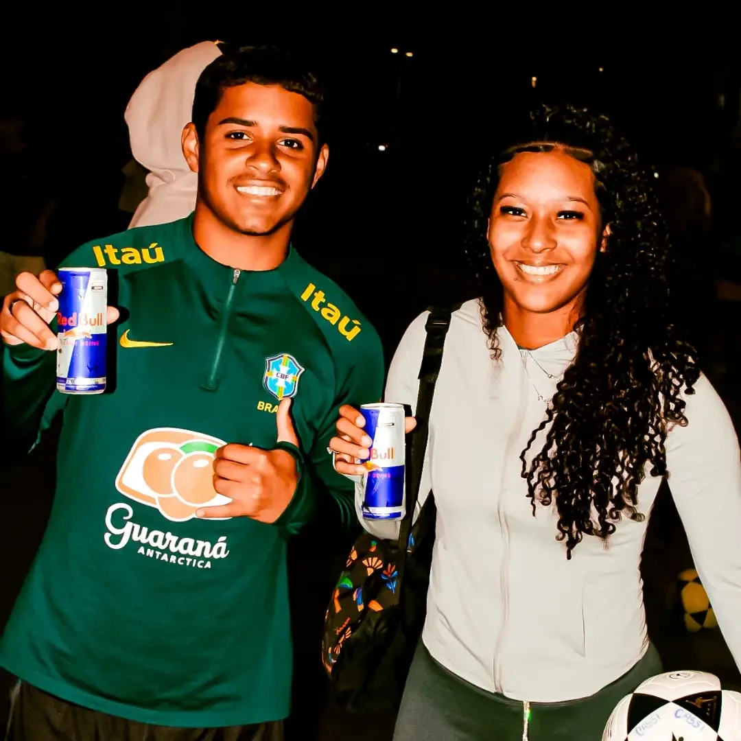 Duas pessoas sorrindo para a câmera durante um evento noturno.