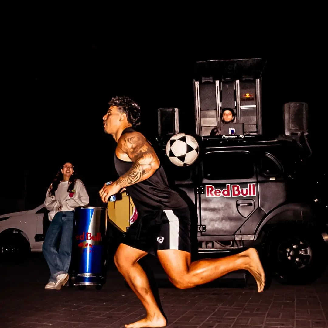 Atleta sem camisa fazendo uma manobra com uma bola de futebol à noite.