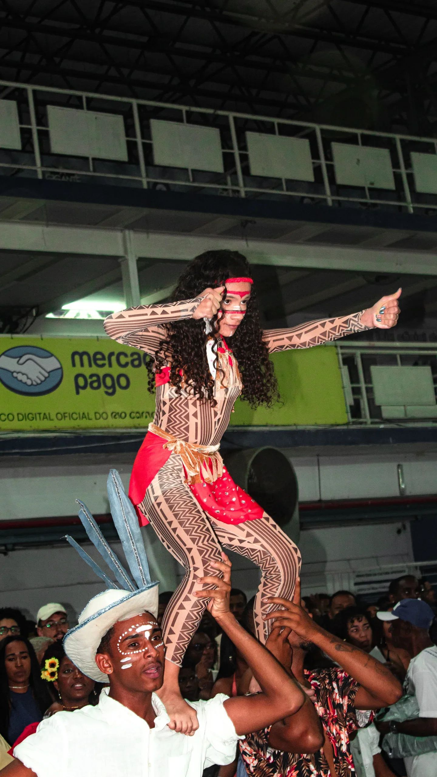 Dançarina de samba com fantasia vermelha e verde em apresentação em uma quadra.