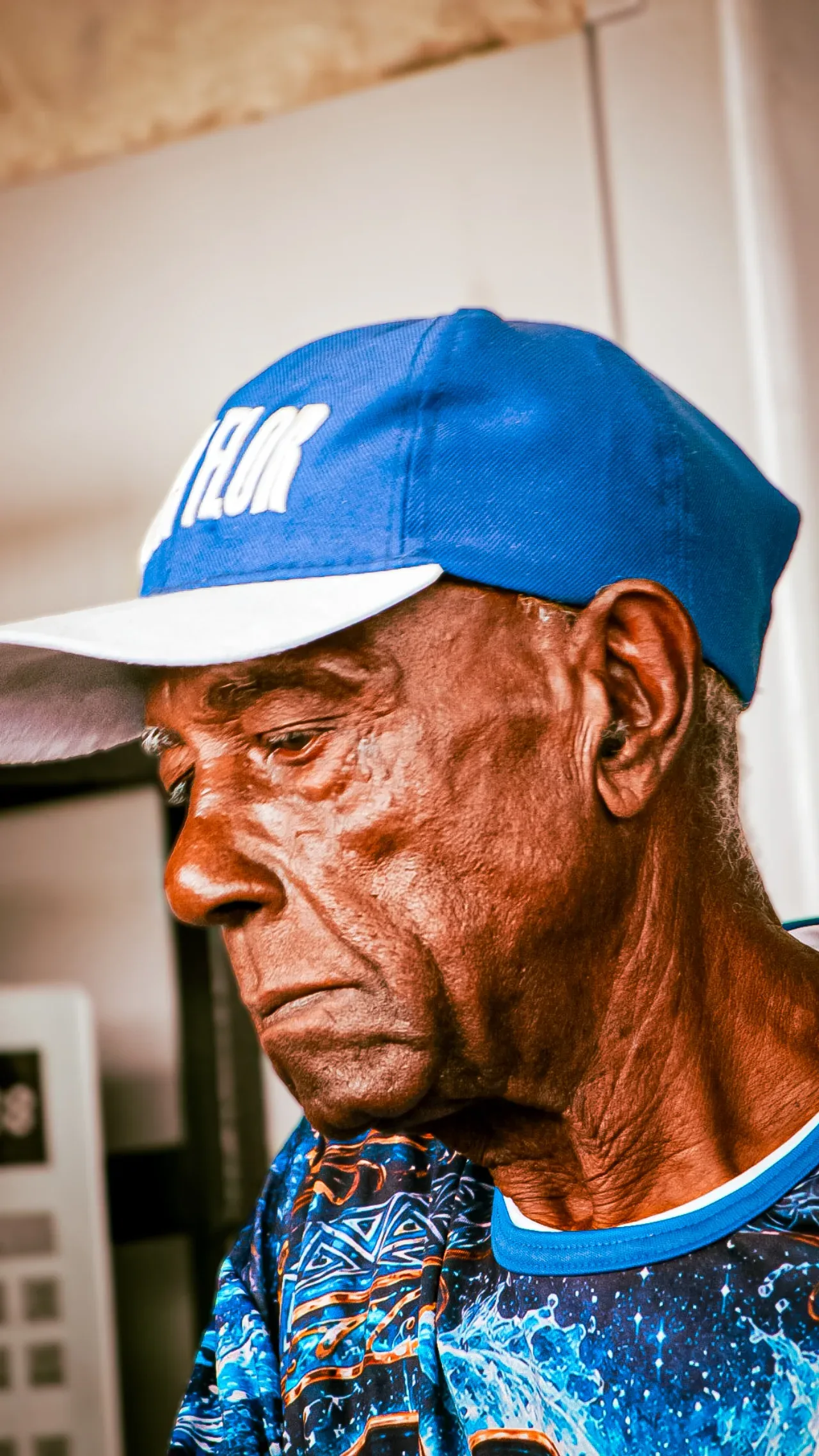Retrato de homem com boné azul, com o rosto iluminado pela luz do sol.
